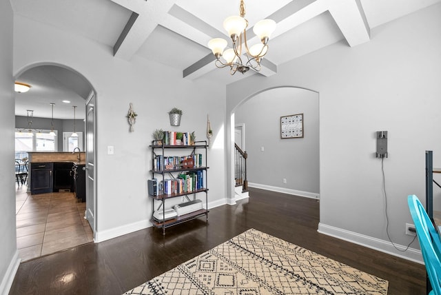 interior space featuring arched walkways, wood finished floors, beam ceiling, and baseboards