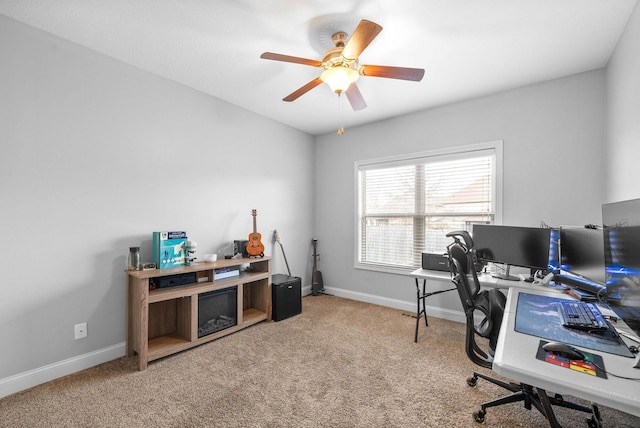 carpeted home office with ceiling fan and baseboards