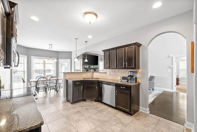 kitchen with arched walkways, a sink, dark brown cabinets, appliances with stainless steel finishes, and decorative backsplash