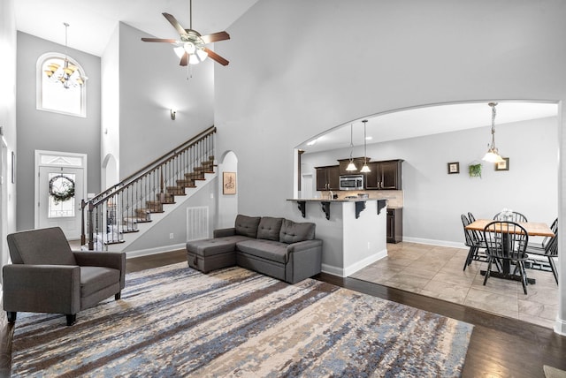 living area featuring visible vents, arched walkways, baseboards, stairway, and wood finished floors