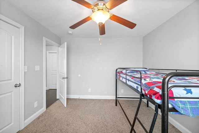 carpeted bedroom with ceiling fan and baseboards