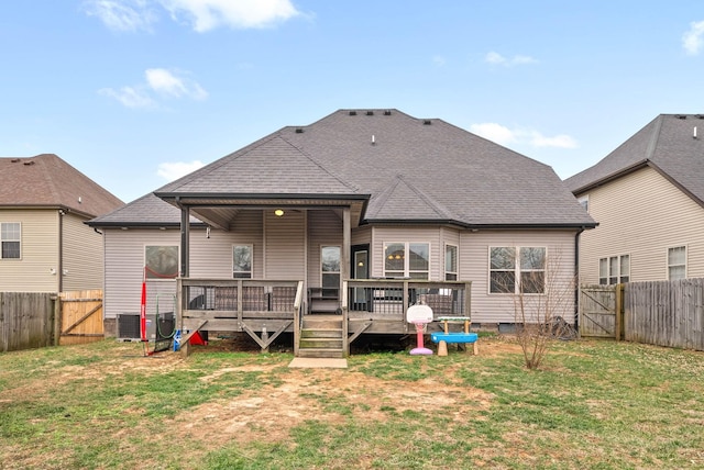 rear view of property with a fenced backyard, a gate, a deck, and a lawn