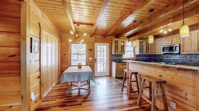 kitchen with stainless steel microwave, wood finished floors, beam ceiling, and decorative backsplash