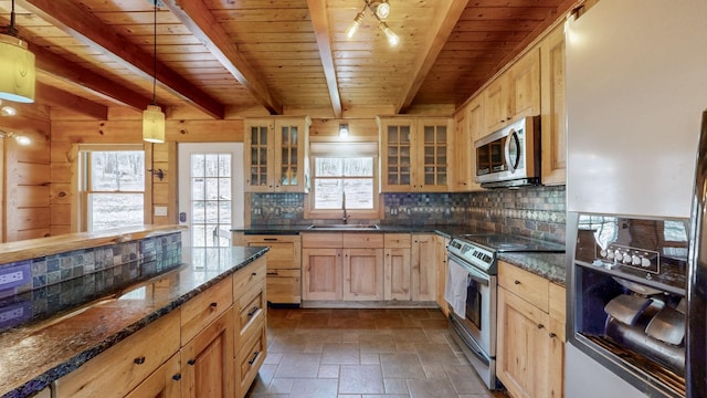 kitchen with stainless steel appliances, tasteful backsplash, light brown cabinetry, stone finish flooring, and a sink