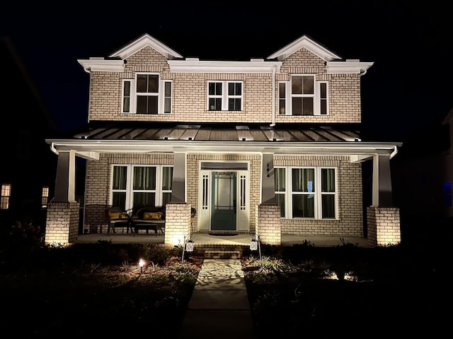 view of front facade featuring covered porch, brick siding, and a standing seam roof