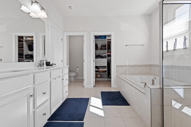 bathroom featuring toilet, tile patterned flooring, visible vents, and a bath