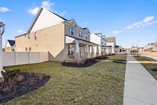 view of side of home featuring a yard, a residential view, brick siding, and fence