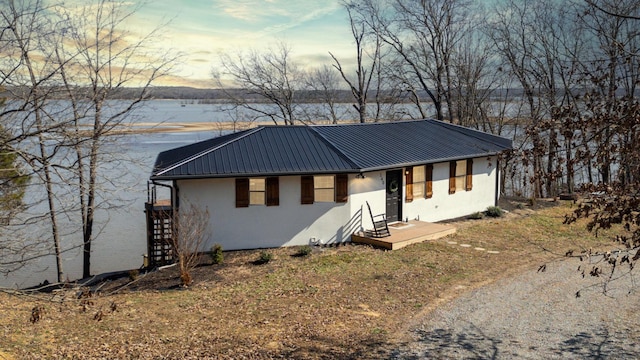 ranch-style home featuring a water view, metal roof, and stucco siding