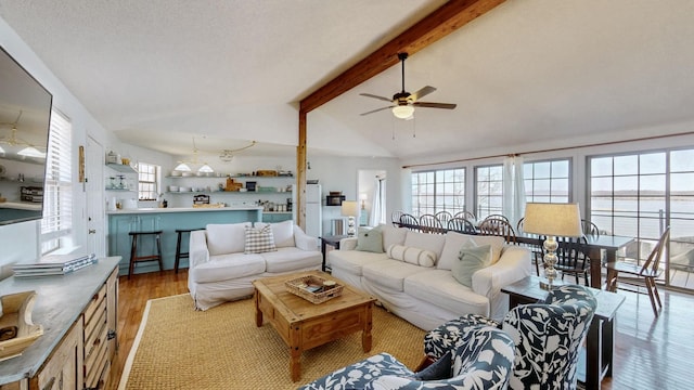 living area featuring lofted ceiling with beams, a healthy amount of sunlight, ceiling fan, and wood finished floors