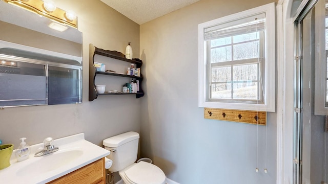 bathroom featuring toilet, an enclosed shower, a textured ceiling, and vanity