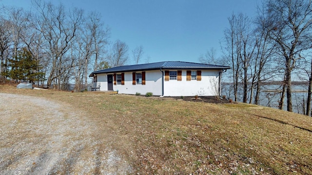 view of front of home with a front yard, metal roof, and stucco siding