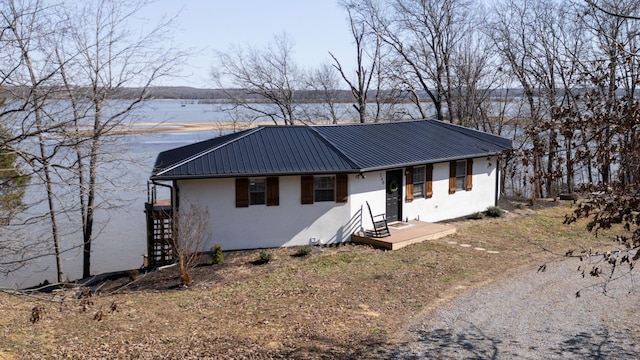 ranch-style home featuring metal roof, a water view, and stucco siding