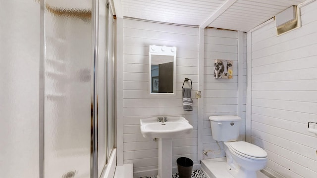 bathroom featuring toilet, a stall shower, and wooden walls