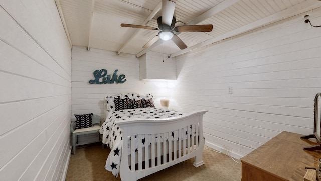 bedroom with a ceiling fan, carpet, and wood walls