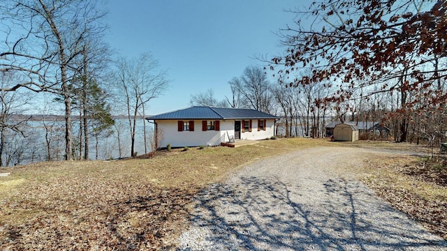 view of front facade with an outbuilding, driveway, a storage unit, and metal roof