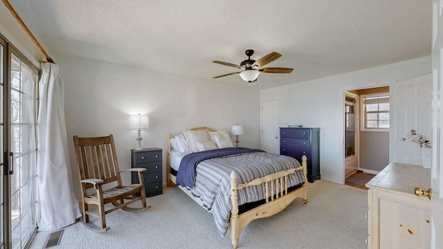 bedroom with light colored carpet, visible vents, ceiling fan, and a textured ceiling