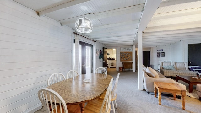 dining space featuring carpet floors, wooden walls, and beamed ceiling