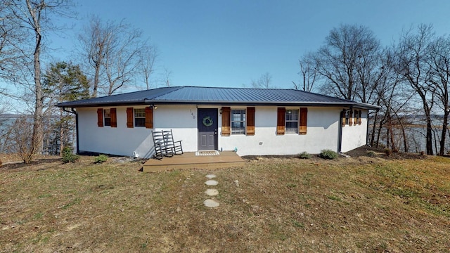 ranch-style home featuring metal roof, a front lawn, and stucco siding