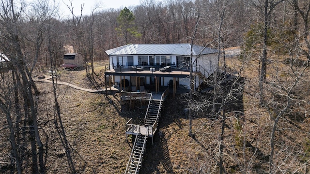 rear view of house featuring a deck, metal roof, a view of trees, and stairs