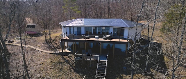 back of house featuring stairs, metal roof, and a view of trees