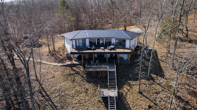 rear view of property featuring a forest view, metal roof, a wooden deck, and stairs