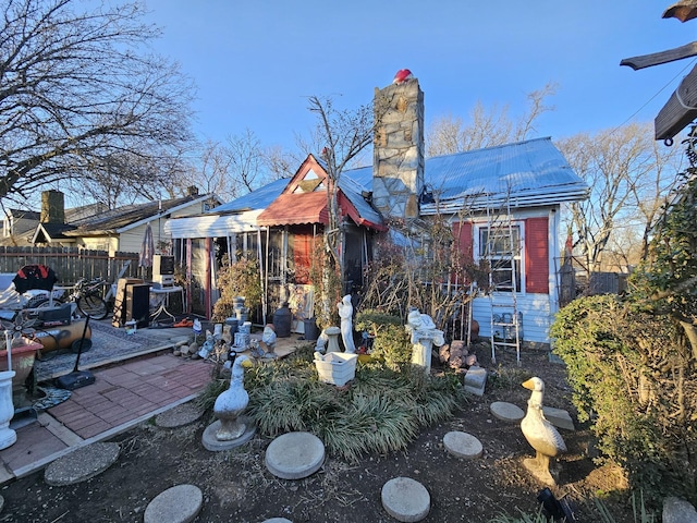 rear view of house with a chimney, fence, metal roof, and a patio