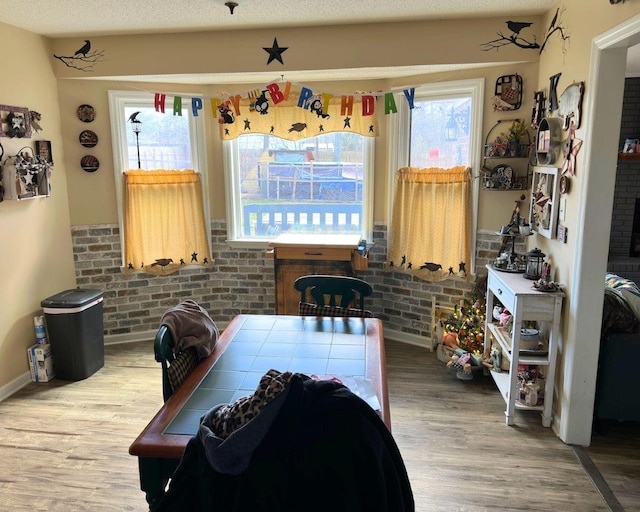 interior space featuring brick wall, wood finished floors, and a wealth of natural light