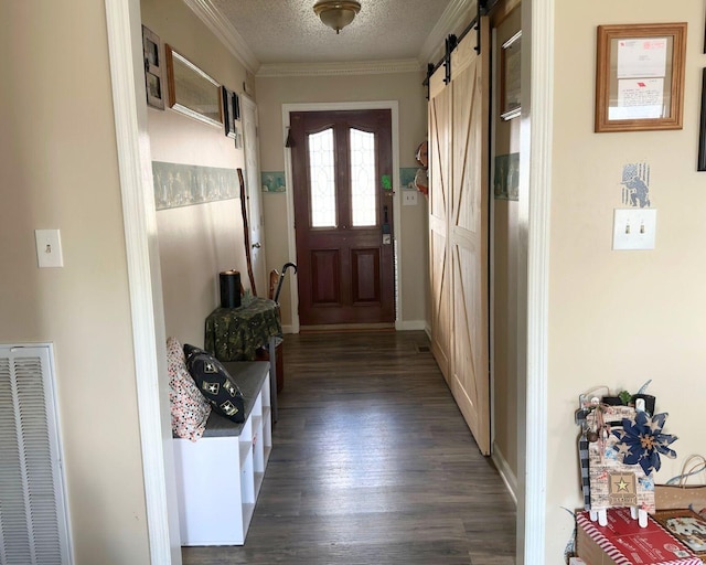 doorway to outside with a textured ceiling, a barn door, visible vents, ornamental molding, and dark wood-style floors