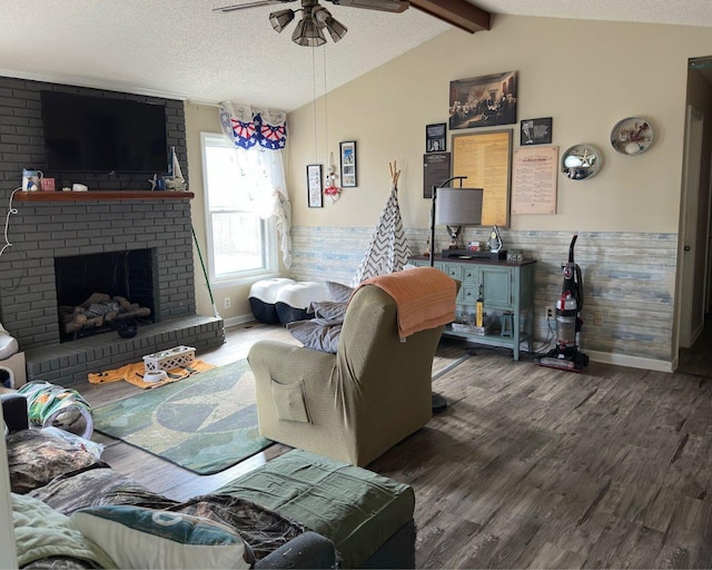 living room with a fireplace, lofted ceiling with beams, wainscoting, a textured ceiling, and wood finished floors