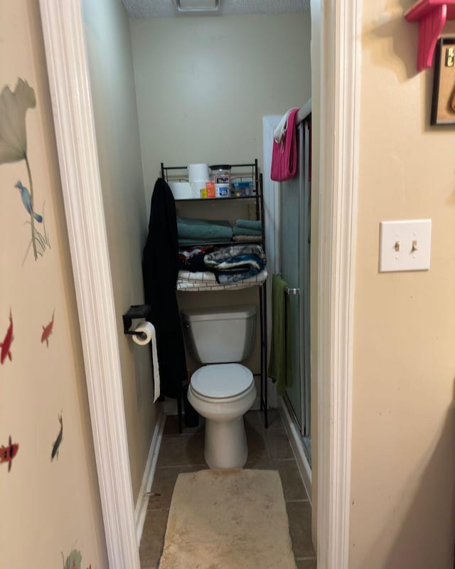 full bath with toilet, a stall shower, and tile patterned floors