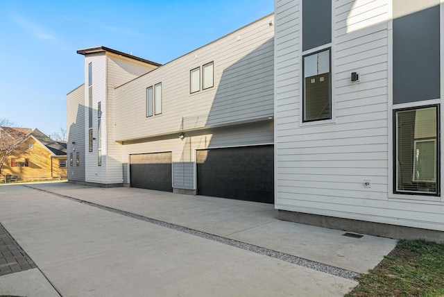 rear view of house featuring an attached garage and concrete driveway