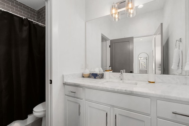 full bath with curtained shower, vanity, and toilet