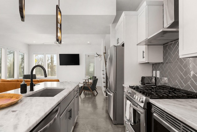 kitchen with concrete flooring, stainless steel appliances, a sink, white cabinetry, and wall chimney exhaust hood