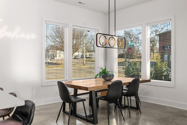 dining space with plenty of natural light, finished concrete floors, and baseboards