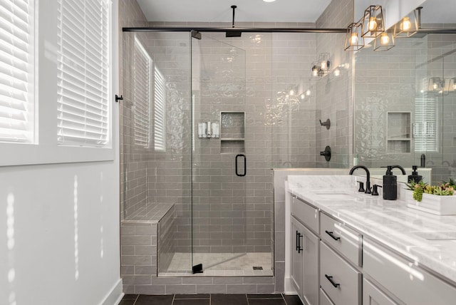 full bath with a shower stall, double vanity, a sink, and tile patterned floors