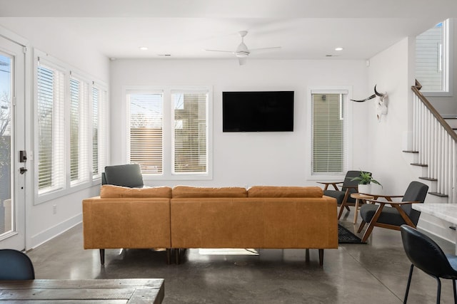 living room with concrete flooring, a wealth of natural light, baseboards, and stairs