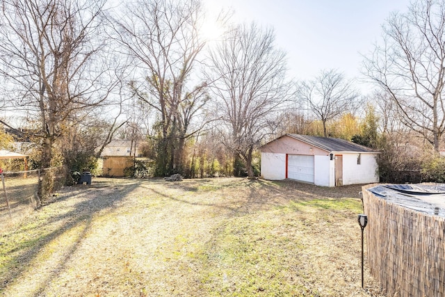 view of yard with a garage, fence, and an outbuilding