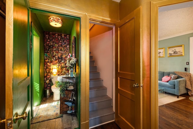 stairs featuring ornamental molding and wood finished floors