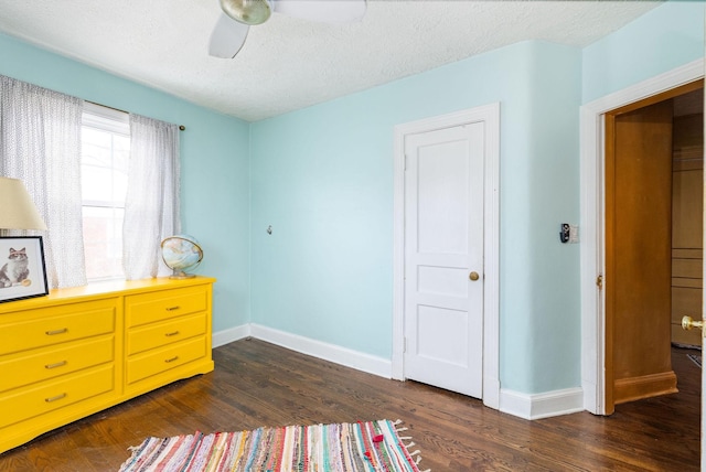 bedroom featuring a ceiling fan, baseboards, a textured ceiling, and dark wood-style floors