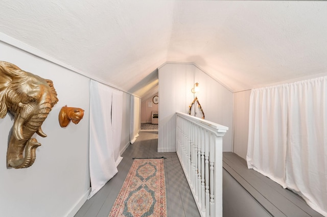 corridor with an upstairs landing and lofted ceiling