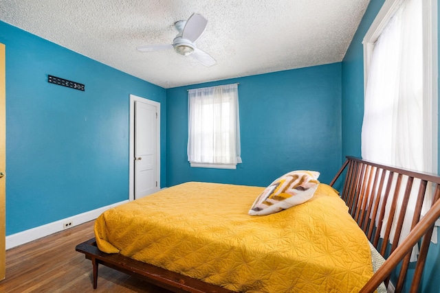 bedroom with baseboards, a textured ceiling, a ceiling fan, and wood finished floors