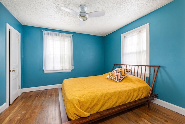 bedroom with wood finished floors, baseboards, and multiple windows