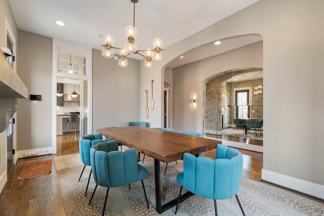 dining space with a chandelier, arched walkways, recessed lighting, and wood finished floors