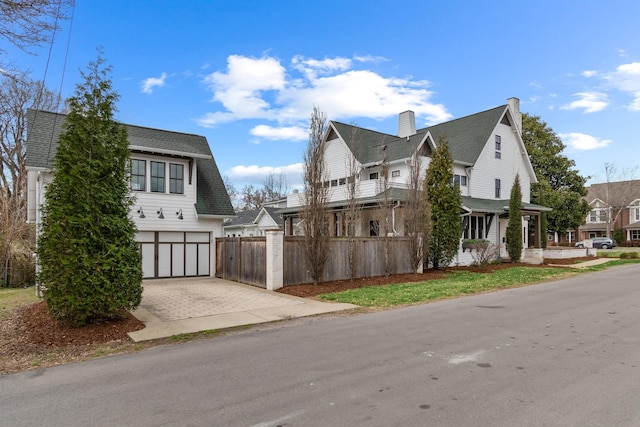 view of home's exterior featuring a garage, decorative driveway, fence, and a shingled roof