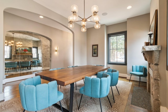 dining room featuring arched walkways, a notable chandelier, recessed lighting, wood finished floors, and baseboards