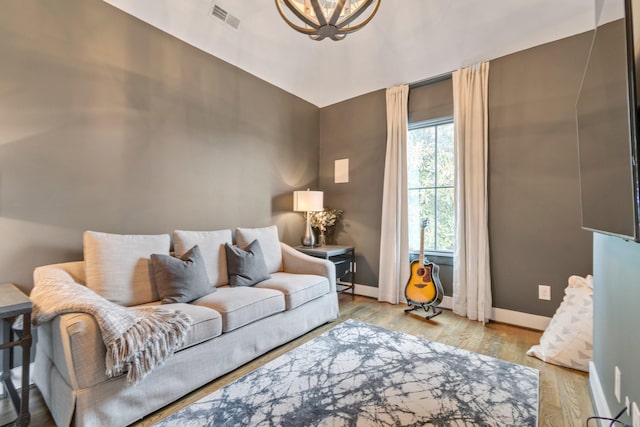 living room with wood finished floors, visible vents, and baseboards