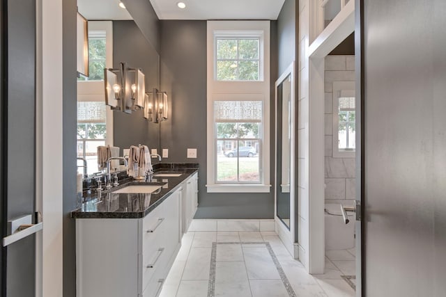 bathroom featuring marble finish floor, a shower with shower door, a sink, and double vanity