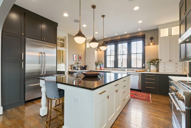 kitchen with white cabinets, a kitchen island, dark wood-style flooring, and premium appliances