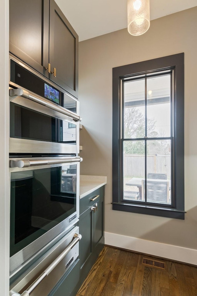 kitchen with stainless steel double oven, visible vents, light countertops, a warming drawer, and dark wood finished floors