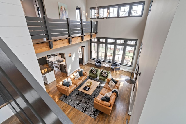 living area featuring baseboards, a high ceiling, wood finished floors, and an inviting chandelier